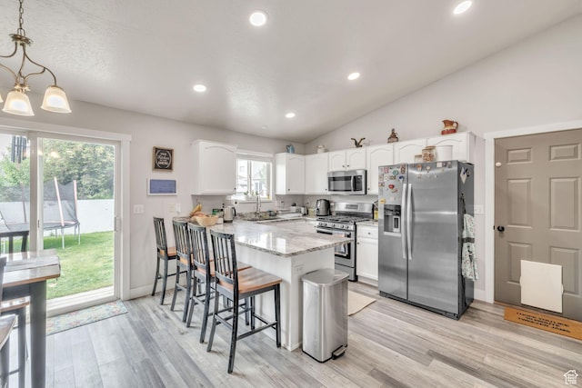 1135 E 220 N, Heber City, UT 84032 - kitchen featuring appliances with stainless steel finishes, a peninsula, a breakfast bar, white cabinets, and light wood-style flooring
