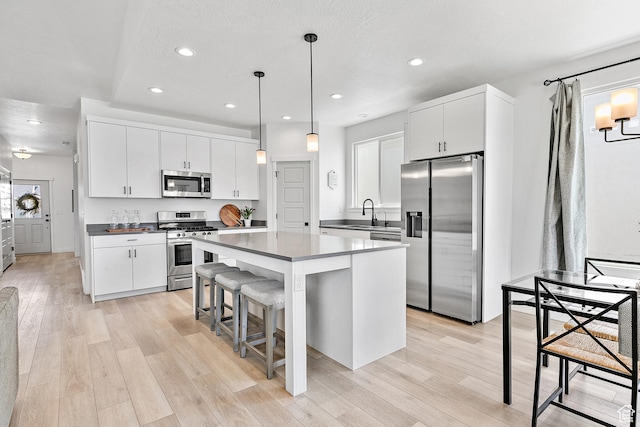 1547 E Cardinal Dr N, Eagle Mountain, UT 84005 - kitchen featuring stainless steel appliances, a center island, dark countertops, a kitchen breakfast bar, and light wood-type flooring