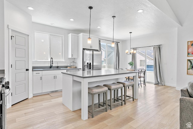 1547 E Cardinal Dr N, Eagle Mountain, UT 84005 - kitchen with appliances with stainless steel finishes, a sink, light wood-style flooring, a kitchen breakfast bar, and white cabinets