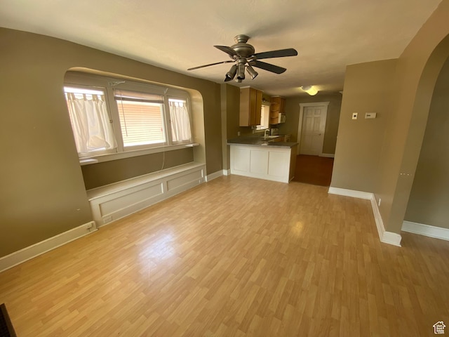 829 E Markea Ave, Salt Lake City, UT 84102 - unfurnished living room with arched walkways, a ceiling fan, light wood-style floors, baseboards, and a sink