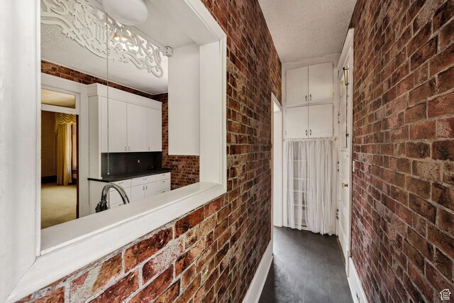 157 N 500 W, Logan, UT 84321 - kitchen featuring brick wall, a textured ceiling, white cabinetry, and a sink