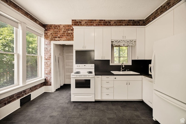157 N 500 W, Logan, UT 84321 - kitchen featuring white appliances, a sink, dark countertops, white cabinetry, and brick wall