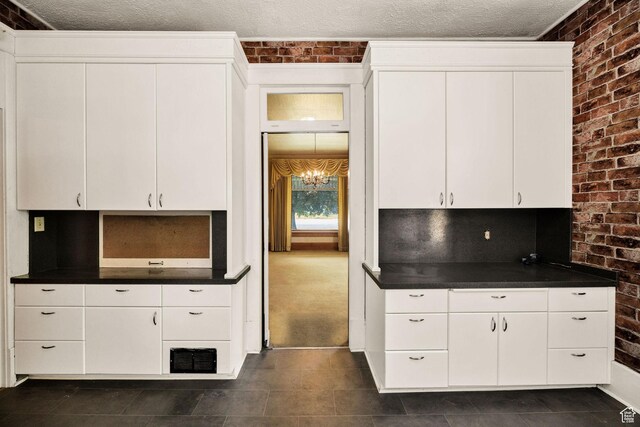 157 N 500 W, Logan, UT 84321 - kitchen with brick wall, dark countertops, white cabinets, dark tile patterned flooring, and a textured ceiling