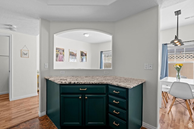 79 W 1970 N, Tooele, UT 84074 - kitchen featuring light countertops, light wood-style floors, green cabinetry, arched walkways, and baseboards