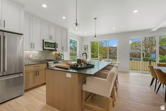 1782 E Bermondsey Ct, Holladay, UT 84117 - kitchen featuring premium appliances, dark countertops, a kitchen island with sink, light wood-type flooring, and recessed lighting