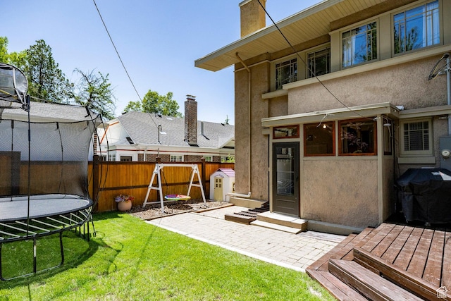 1376 E Perry Ave, Salt Lake City, UT 84103 - rear view of house featuring a trampoline, stucco siding, a chimney, and a patio area