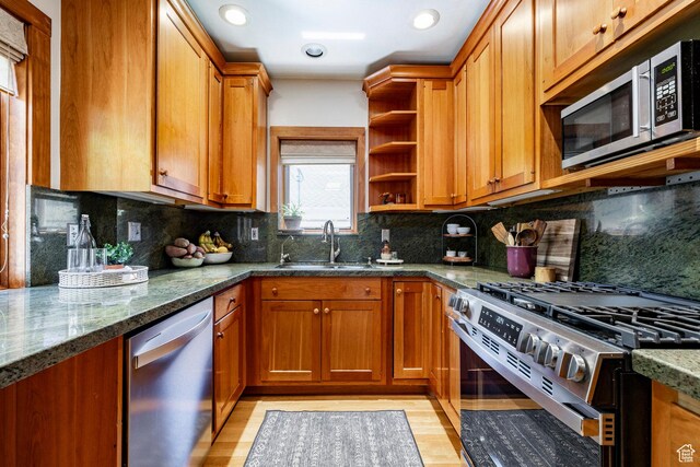 1376 E Perry Ave, Salt Lake City, UT 84103 - kitchen with stainless steel appliances, brown cabinets, open shelves, dark stone countertops, and light wood-style flooring