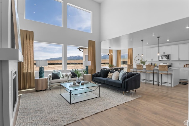 250 S Cherry Hl Unit 228, Grantsville, UT 84029 - living room featuring plenty of natural light, a mountain view, light wood-style flooring, a chandelier, and a high ceiling