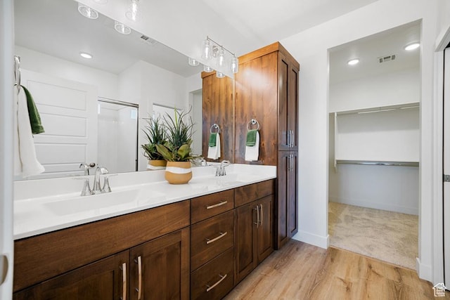 6068 S White Trails Dr, St George, UT 84790 - bathroom with double vanity, a spacious closet, wood finished floors, a shower with shower door, and baseboards