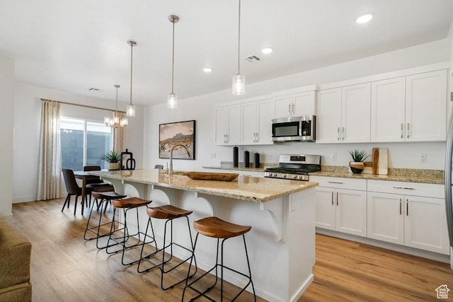 6068 S White Trails Dr, St George, UT 84790 - kitchen with stainless steel appliances, light wood-type flooring, a kitchen breakfast bar, white cabinets, and recessed lighting