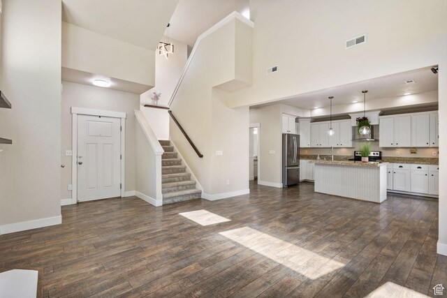 101 E Mansonia Dr S, Draper, UT 84020 - kitchen featuring appliances with stainless steel finishes, a towering ceiling, dark wood-style flooring, a kitchen island, and white cabinets