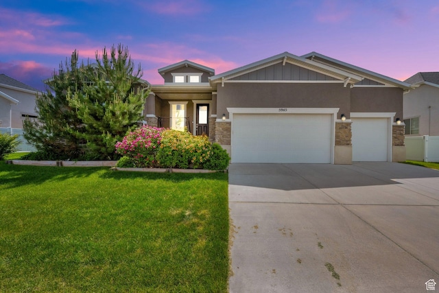 5945 N Spring St, Stansbury Park, UT 84074 - view of front of house with stone siding, a front lawn, an attached garage, driveway, and stucco siding