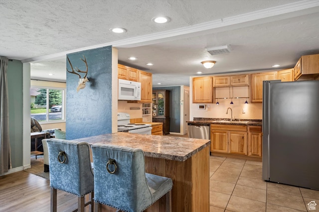 1225 E 5th St, Ogden, UT 84404 - kitchen featuring appliances with stainless steel finishes, a sink, a textured ceiling, a kitchen bar, and a peninsula