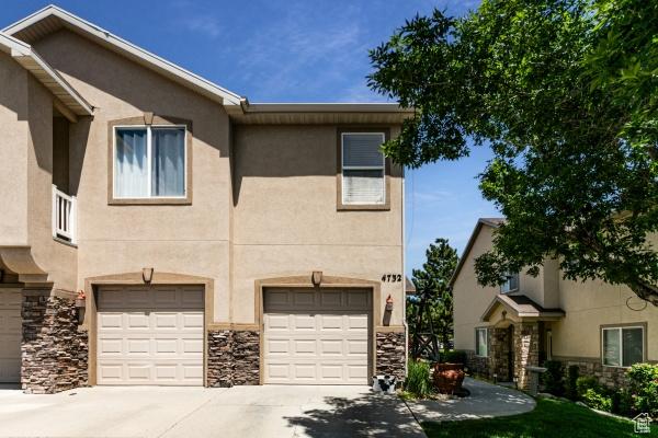 4732 W Wagon Train Dr, Herriman, UT 84096 - townhome / multi-family property featuring driveway, stone siding, a garage, and stucco siding