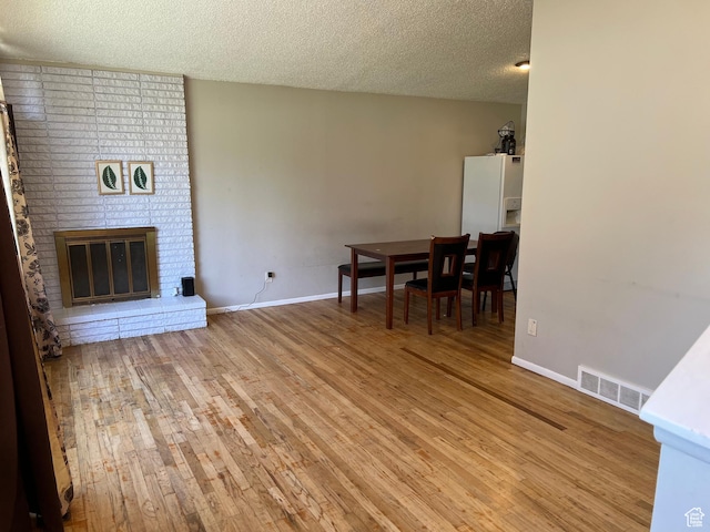 3291 S 4000 W, West Valley City, UT 84120 - unfurnished living room featuring light wood-style floors, a textured ceiling, baseboards, and a brick fireplace