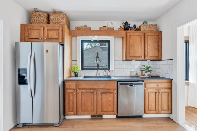 1440 E 1300 S, Salt Lake City, UT 84105 - kitchen with appliances with stainless steel finishes, a sink, light wood-style flooring, and decorative backsplash