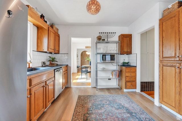 1440 E 1300 S, Salt Lake City, UT 84105 - kitchen with stainless steel appliances, light wood-style floors, tasteful backsplash, and brown cabinetry
