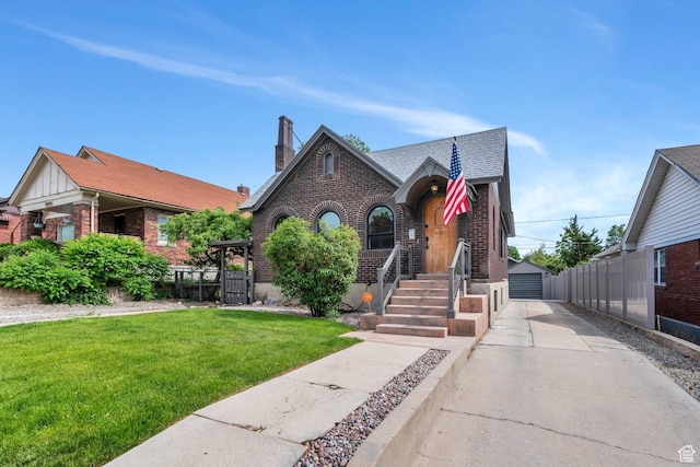 1440 E 1300 S, Salt Lake City, UT 84105 - tudor-style house with brick siding, a front yard, an outbuilding, a detached garage, and roof with shingles