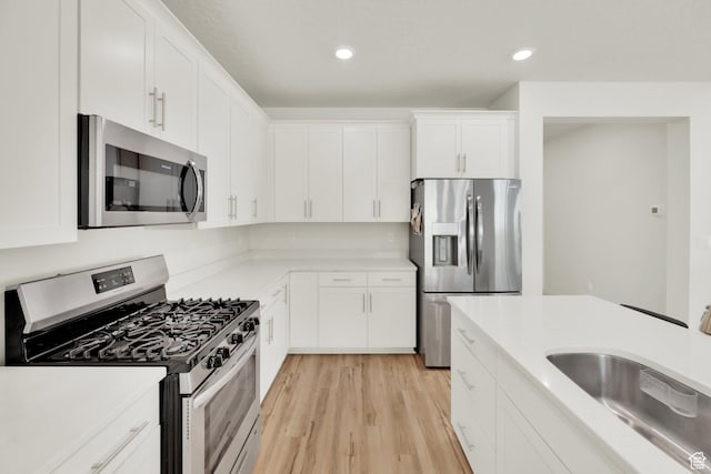 7405 W Glowing Sky Dr S, West Valley City, UT 84081 - kitchen featuring stainless steel appliances, a sink, light wood-style floors, white cabinetry, and light countertops