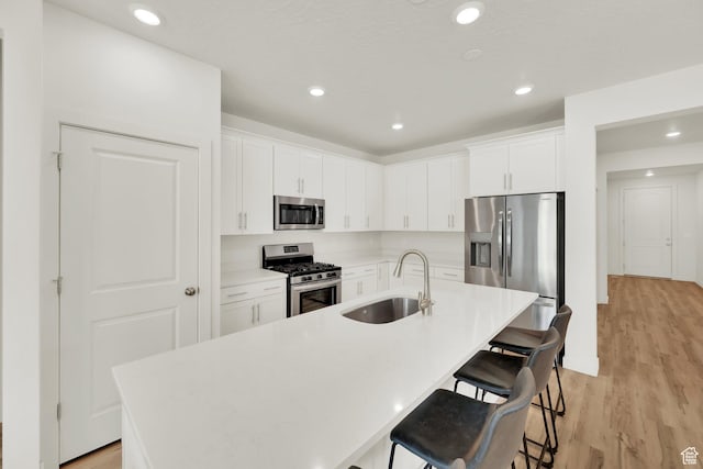 7405 W Glowing Sky Dr S, West Valley City, UT 84081 - kitchen featuring appliances with stainless steel finishes, a sink, light wood-style floors, a breakfast bar area, and white cabinetry