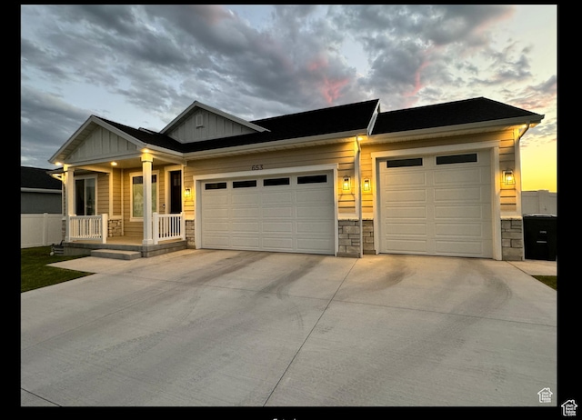 653 S 340 E, Smithfield, UT 84335 - view of front of property featuring a porch, a garage, board and batten siding, concrete driveway, and stone siding