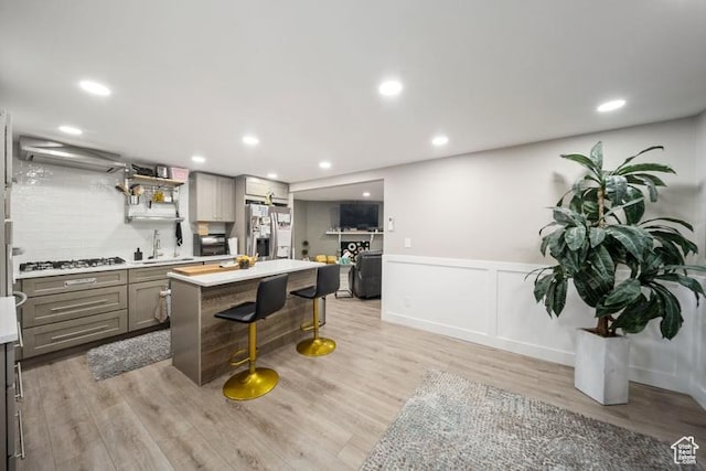 2341 E Neffs Ln S, Millcreek, UT 84109 - kitchen featuring stainless steel refrigerator with ice dispenser, gray cabinets, a breakfast bar, light wood-style floors, and light countertops