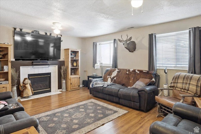 1158 N 2675 W, Layton, UT 84041 - living area with a textured ceiling, wood finished floors, a tiled fireplace, and ceiling fan