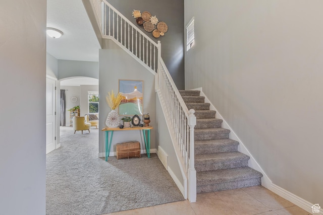 2869 W Chestnut St, Lehi, UT 84043 - staircase with arched walkways, carpet, baseboards, a towering ceiling, and tile patterned flooring