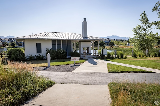 4937 W Calton Ln S, South Jordan, UT 84009 - view of front facade featuring a standing seam roof, a chimney, a mountain view, stucco siding, and metal roof