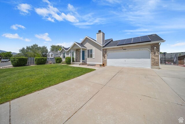 6262 W Contadora Dr S, West Valley City, UT 84128 - view of front of home with concrete driveway, roof mounted solar panels, an attached garage, a chimney, and brick siding