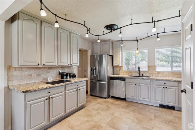 320 E 4600 S, Washington Terrace, UT 84405 - kitchen with appliances with stainless steel finishes, a sink, decorative backsplash, light stone countertops, and light tile patterned floors