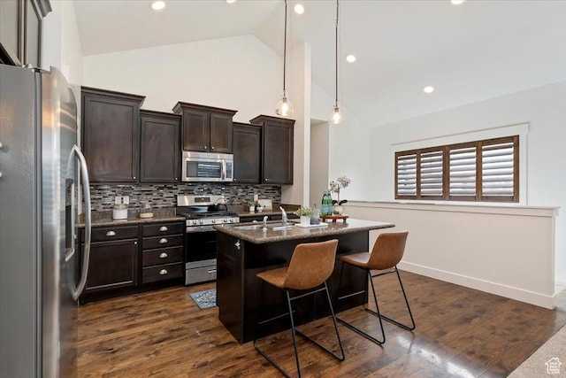 1918 W City Village Way Unit 140, Riverton, UT 84065 - kitchen with stainless steel appliances, backsplash, a kitchen bar, dark brown cabinetry, and a center island with sink