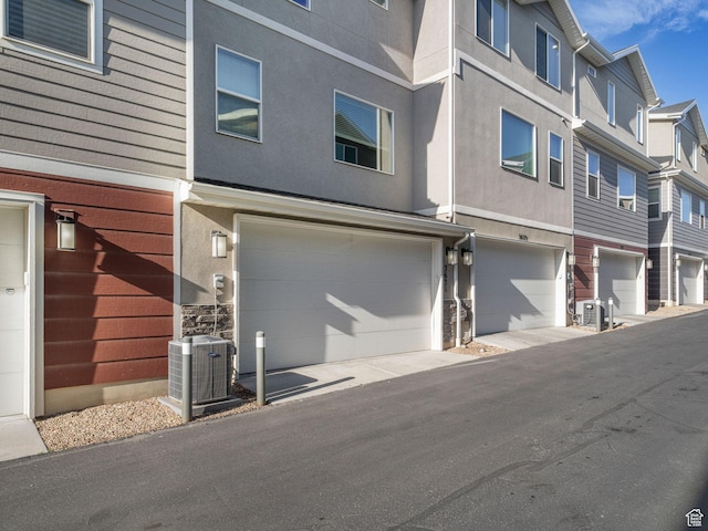3671 W Sunrise Sky Ln Unit 1022, South Jordan, UT 84009 - view of front of house featuring cooling unit, a garage, a residential view, stone siding, and stucco siding