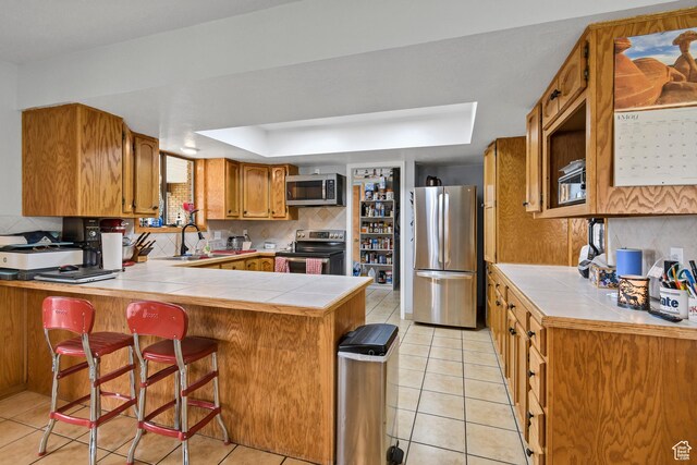 155 S 200 W, Gunnison, UT 84634 - kitchen featuring appliances with stainless steel finishes, a tray ceiling, a sink, a peninsula, and decorative backsplash