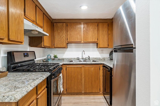 531 S 900 E Unit B2, Salt Lake City, UT 84102 - kitchen with stainless steel appliances, a sink, under cabinet range hood, light wood finished floors, and brown cabinets