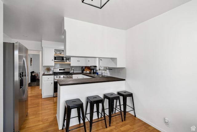 345 W 300 N, Richfield, UT 84701 - kitchen featuring stainless steel appliances, dark countertops, a peninsula, light wood-type flooring, and white cabinetry