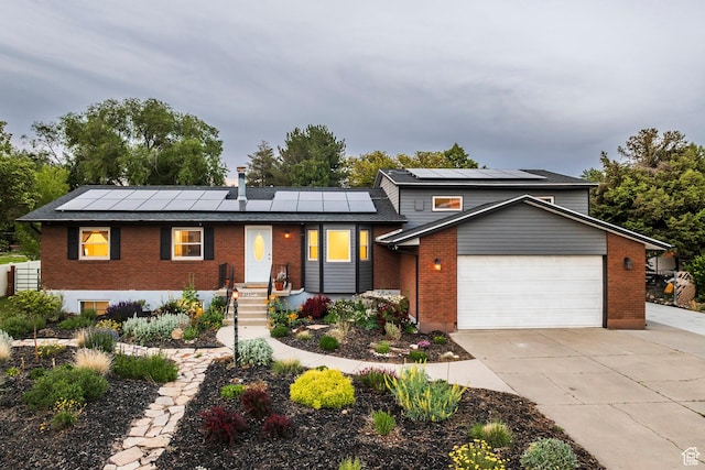 10297 S Weeping Willow Dr E, Sandy, UT 84070 - view of front of home featuring brick siding, roof mounted solar panels, an attached garage, and driveway
