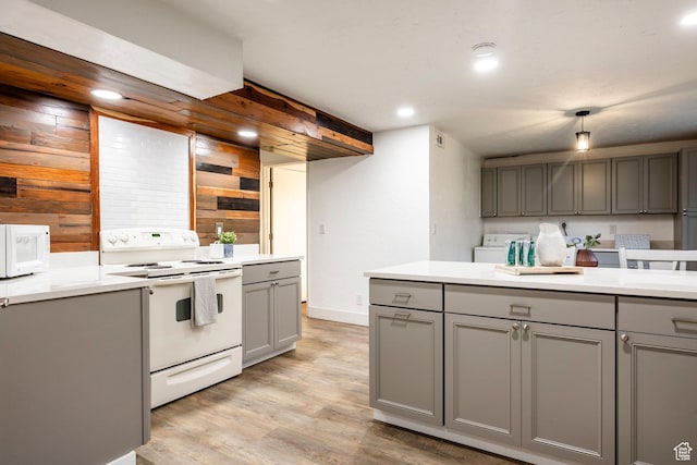 10297 S Weeping Willow Dr E, Sandy, UT 84070 - kitchen with gray cabinetry, white appliances, separate washer and dryer, wood walls, and light wood-style floors