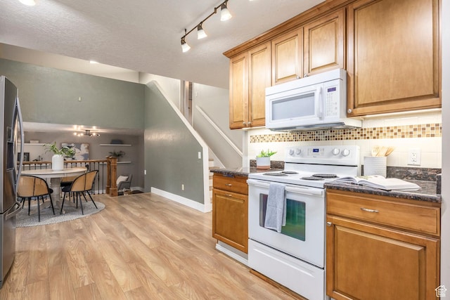 10297 S Weeping Willow Dr E, Sandy, UT 84070 - kitchen featuring white appliances, decorative backsplash, light wood-style flooring, brown cabinets, and baseboards