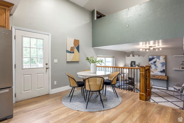 10297 S Weeping Willow Dr E, Sandy, UT 84070 - dining room featuring light wood-style flooring, a towering ceiling, and baseboards