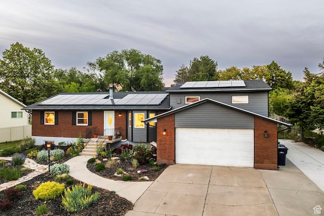 10297 S Weeping Willow Dr E, Sandy, UT 84070 - view of front of home with brick siding, roof mounted solar panels, a garage, and driveway