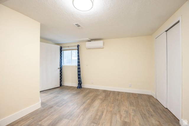 10297 S Weeping Willow Dr E, Sandy, UT 84070 - unfurnished bedroom featuring a wall unit AC, wood finished floors, baseboards, a textured ceiling, and a closet