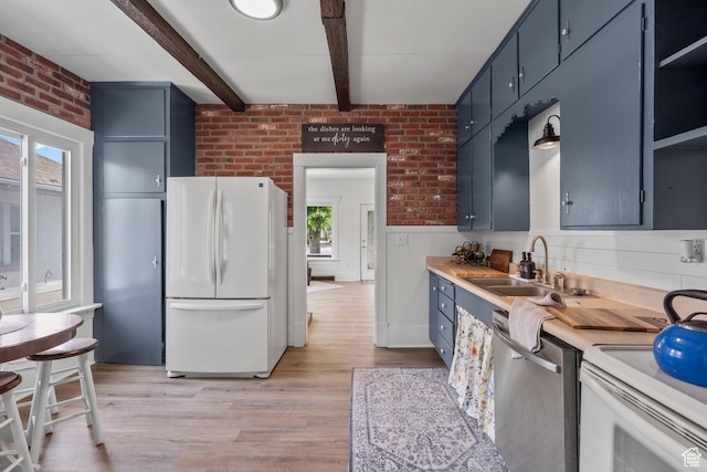 2955 S Jefferson Ave E, Ogden, UT 84403 - kitchen with freestanding refrigerator, stainless steel dishwasher, a sink, blue cabinetry, and brick wall