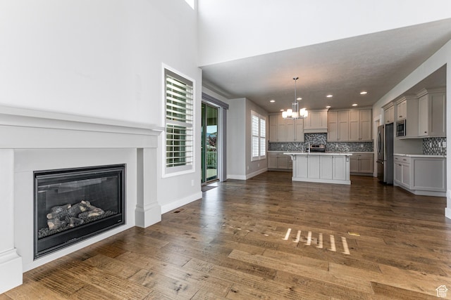 1065 S 425 W, Farmington, UT 84025 - unfurnished living room featuring a chandelier, a glass covered fireplace, dark wood-style flooring, recessed lighting, and baseboards