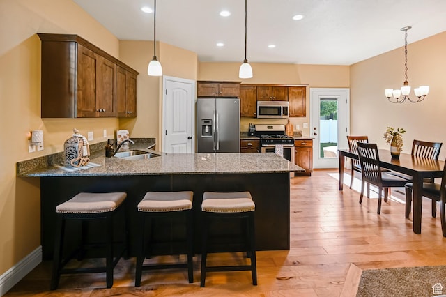 658 S 150 E, Smithfield, UT 84335 - kitchen featuring appliances with stainless steel finishes, a sink, a peninsula, light wood-style floors, and decorative light fixtures