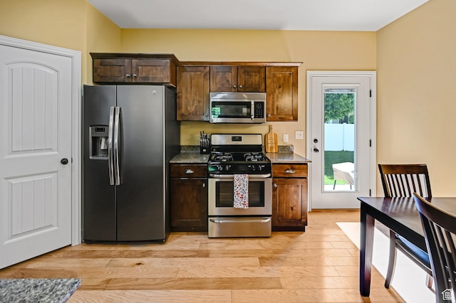658 S 150 E, Smithfield, UT 84335 - kitchen with appliances with stainless steel finishes, light wood finished floors, dark brown cabinets, and dark stone counters