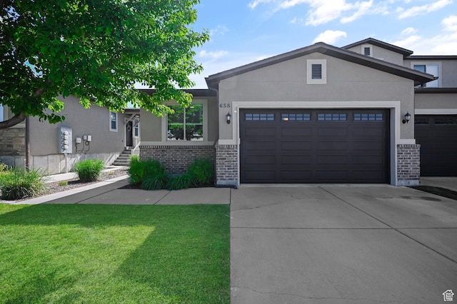 658 S 150 E, Smithfield, UT 84335 - view of front of home with brick siding, a garage, driveway, a front yard, and stucco siding