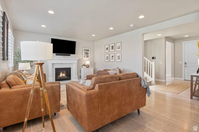 1295 E Granite Peak Rd, Eagle Mountain, UT 84005 - living area with stairway, recessed lighting, light wood finished floors, a glass covered fireplace, and baseboards