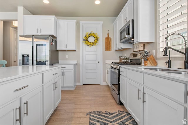 1295 E Granite Peak Rd, Eagle Mountain, UT 84005 - kitchen with appliances with stainless steel finishes, a sink, recessed lighting, light wood-style floors, and white cabinetry