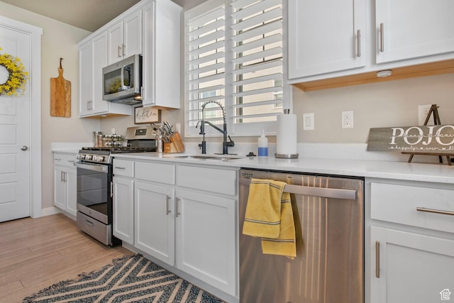 1295 E Granite Peak Rd, Eagle Mountain, UT 84005 - kitchen featuring appliances with stainless steel finishes, a sink, light countertops, white cabinetry, and light wood-style floors